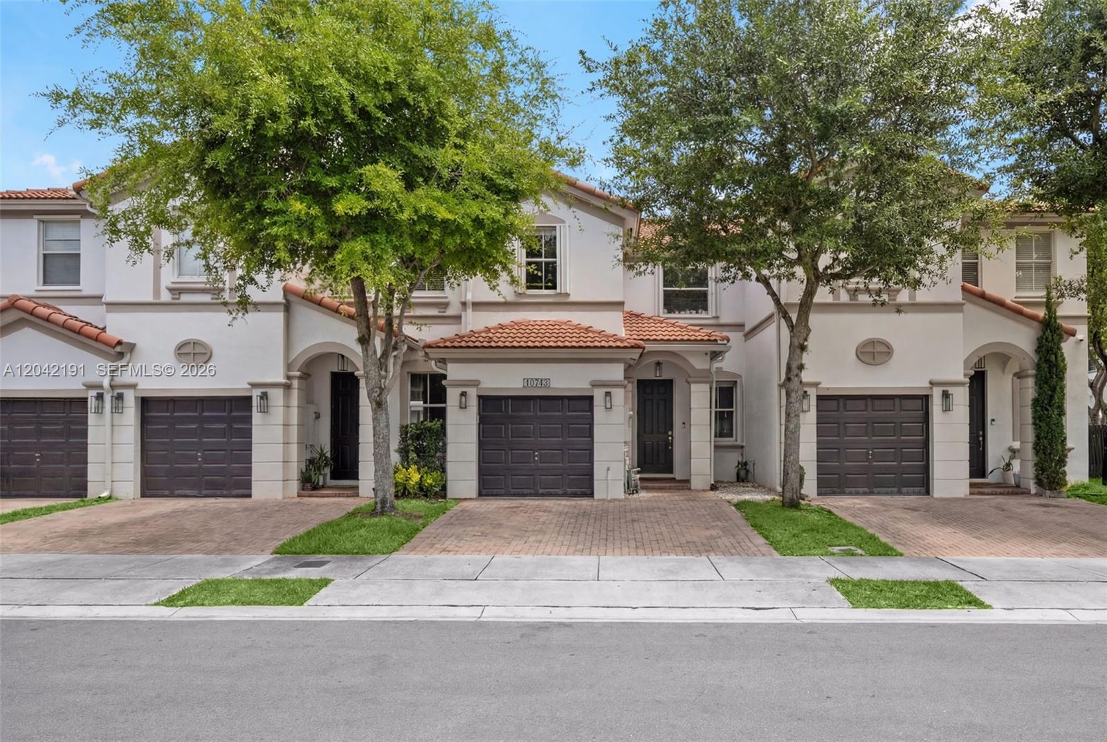 A row of three two-story townhouses with brown garage doors and terracotta-tiled roofs — 10743 NW 78th Ter, Doral FL 33178, DORAL, FL