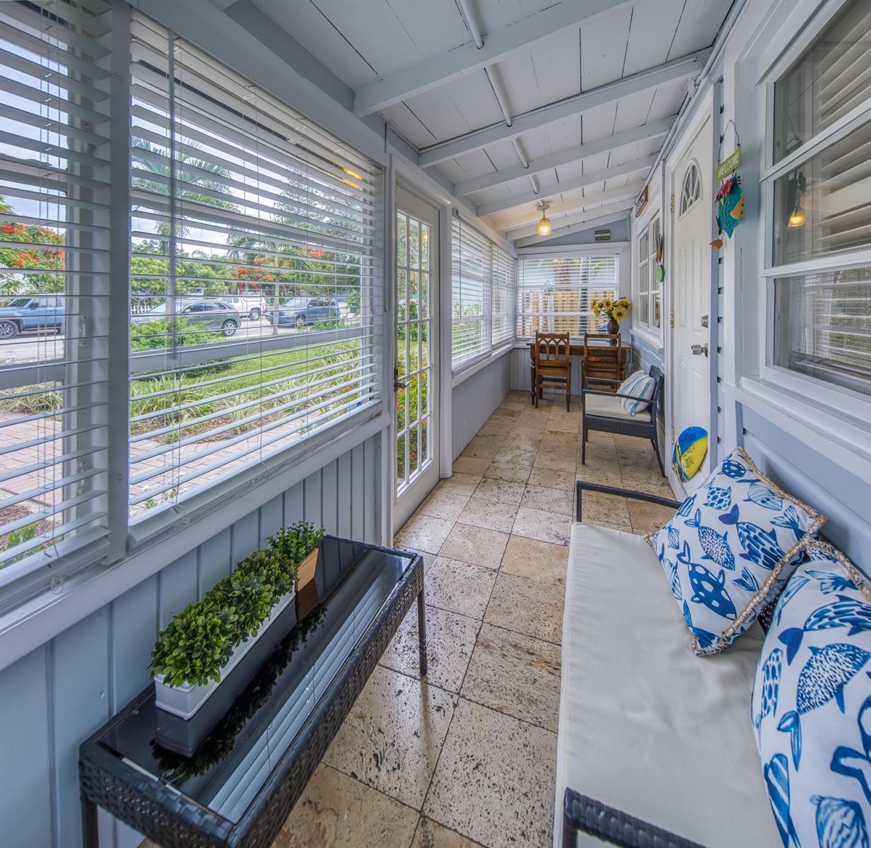 A light-filled sunroom features tile flooring, white wood-paneled walls, and a view of the street — 523 N K Street, FL 33460, FL