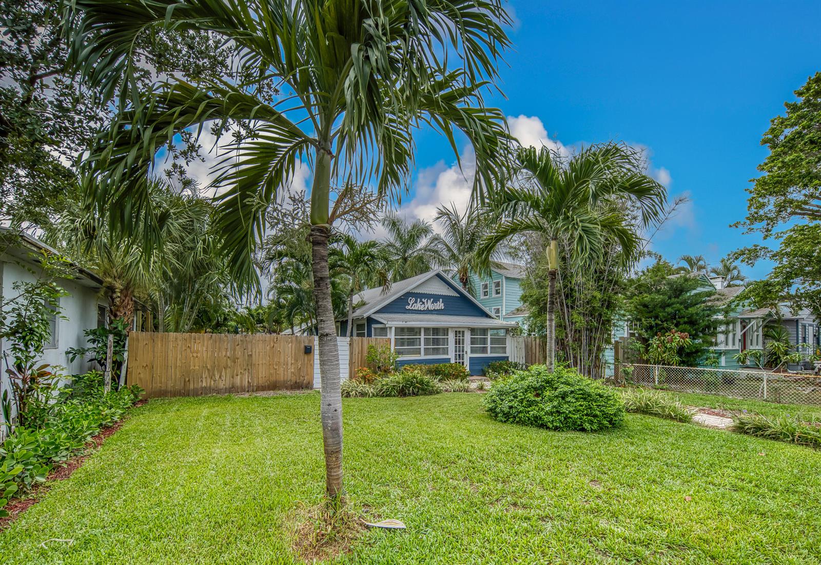 A blue house with a Lake Worth sign sits behind a wooden fence and lawn — 523 N K Street, FL 33460, FL
