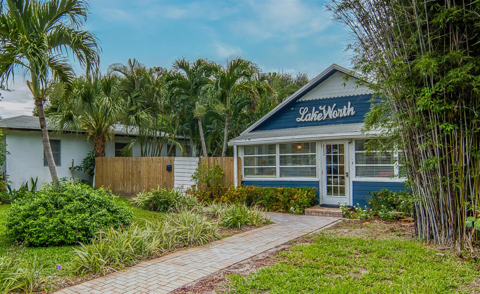 A blue house with a brick walkway and palm trees in a tropical yard — 523 N K Street, FL 33460, FL