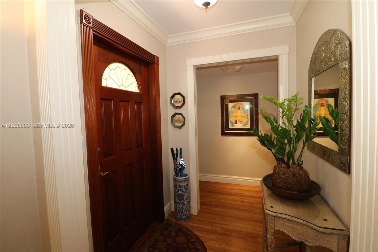 An entryway features a wooden front door, hardwood flooring, a console table, and wall art — 6160 SW 84th St, South Miami FL 33143, SOUTH MIAMI, FL
