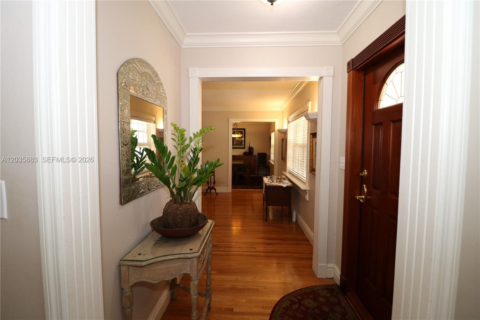 A foyer with hardwood floors, a console table, a mirror, and a wooden front door — 6160 SW 84th St, South Miami FL 33143, SOUTH MIAMI, FL
