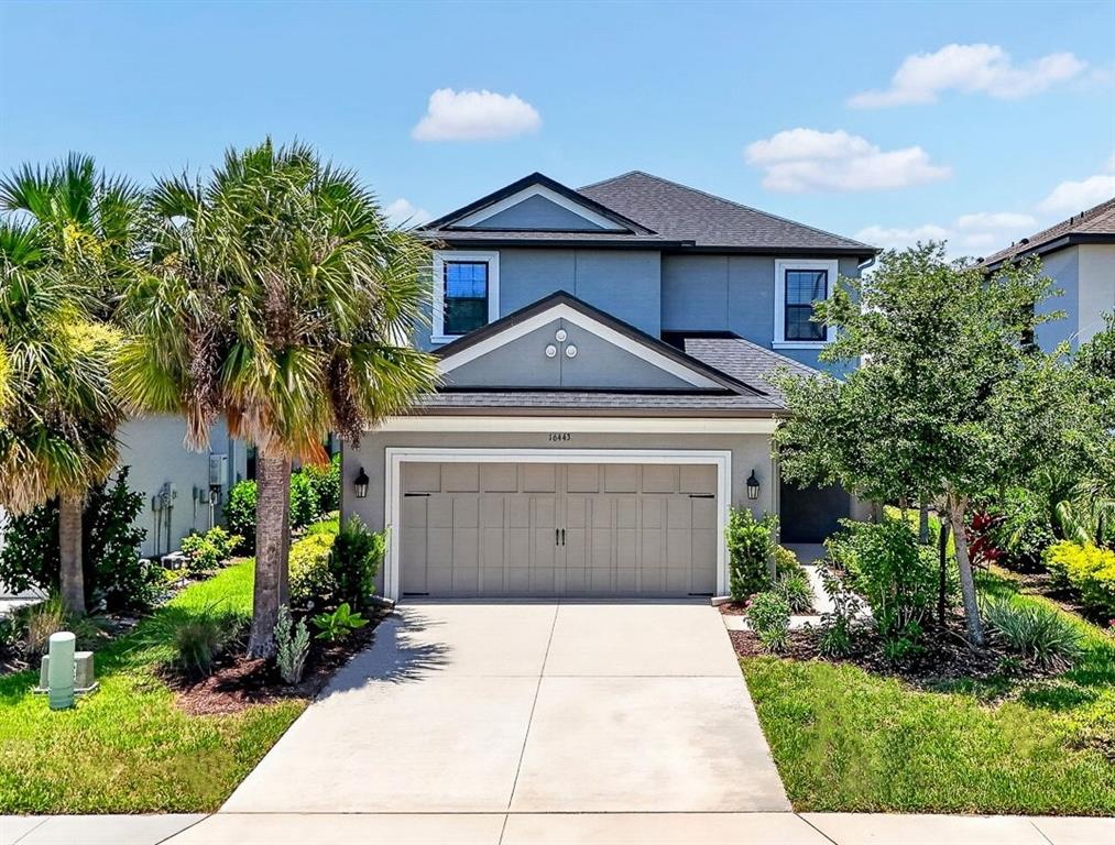 A two-story suburban house with a gray exterior, a two-car garage, and a palm tree — 16443 PAYNES MILL DRIVE, BRADENTON, FL