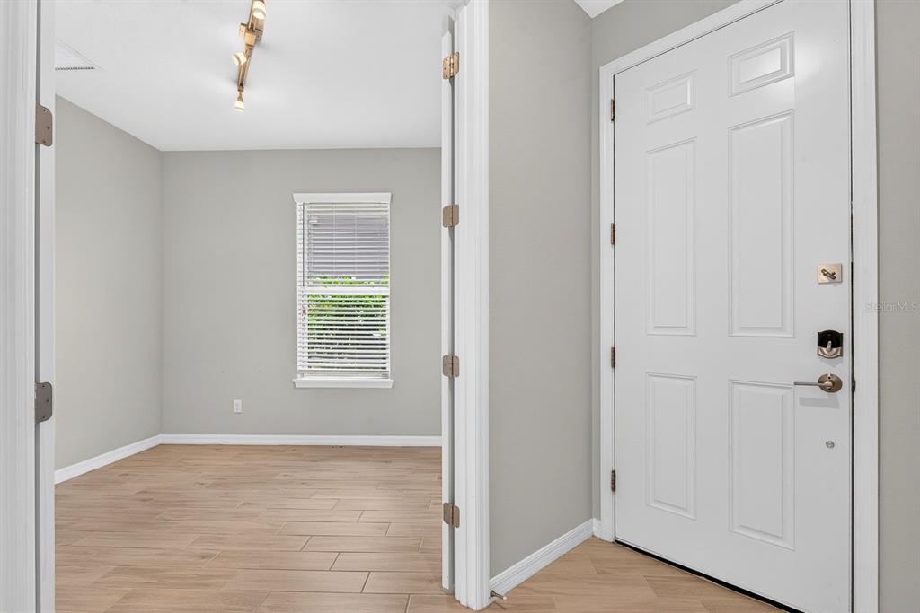 An entryway with a white door leads into a room with light wood-look flooring — 16443 PAYNES MILL DRIVE, BRADENTON, FL