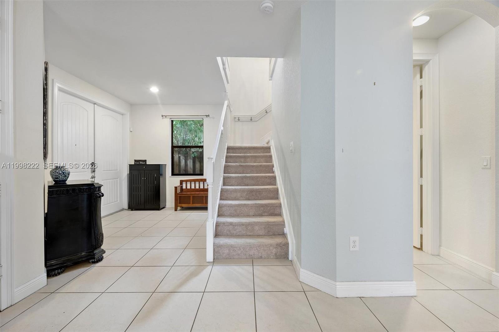 An entryway features light tile flooring, a carpeted staircase, and a black storage cabinet — 8755 NW 102nd Ct, Doral FL 33178, DORAL, FL