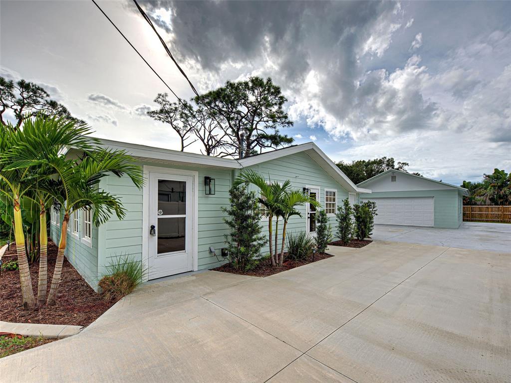 A light green house with a white door and a detached garage under a cloudy sky — 415 YALE STREET, ENGLEWOOD, FL