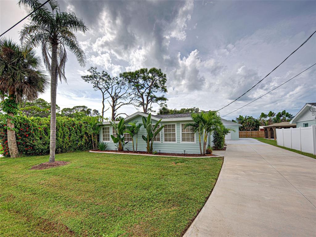 A light green single-story house with a concrete driveway and palm trees in the yard — 415 YALE STREET, ENGLEWOOD, FL