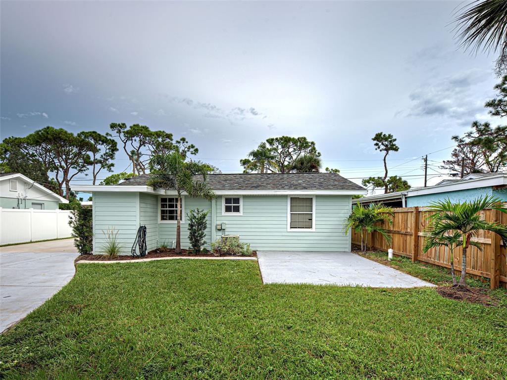 The exterior of a light green house features a concrete patio and a wooden fence — 415 YALE STREET, ENGLEWOOD, FL