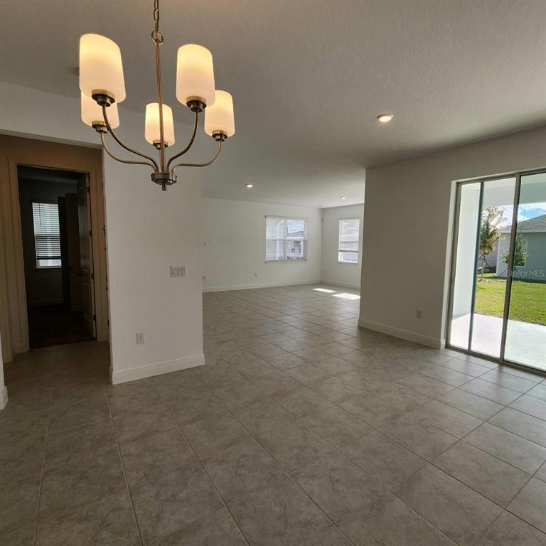 An open-concept living area features light tile flooring, a chandelier, and sliding glass doors — 19050 BLUELEAF STREET, ORLANDO, FL