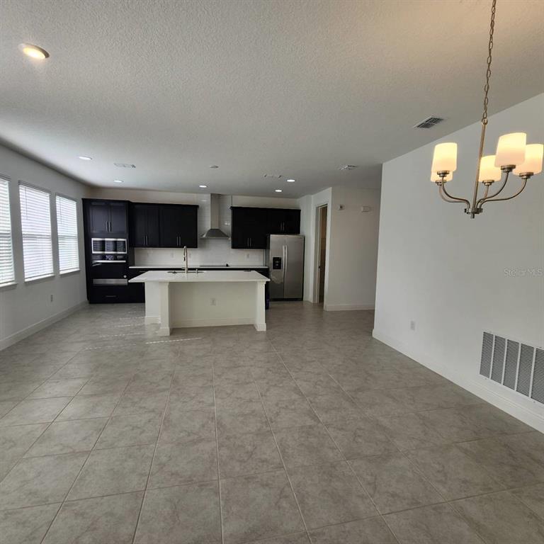 A kitchen with dark cabinets, a white island, and tile flooring in an open room — 19050 BLUELEAF STREET, ORLANDO, FL