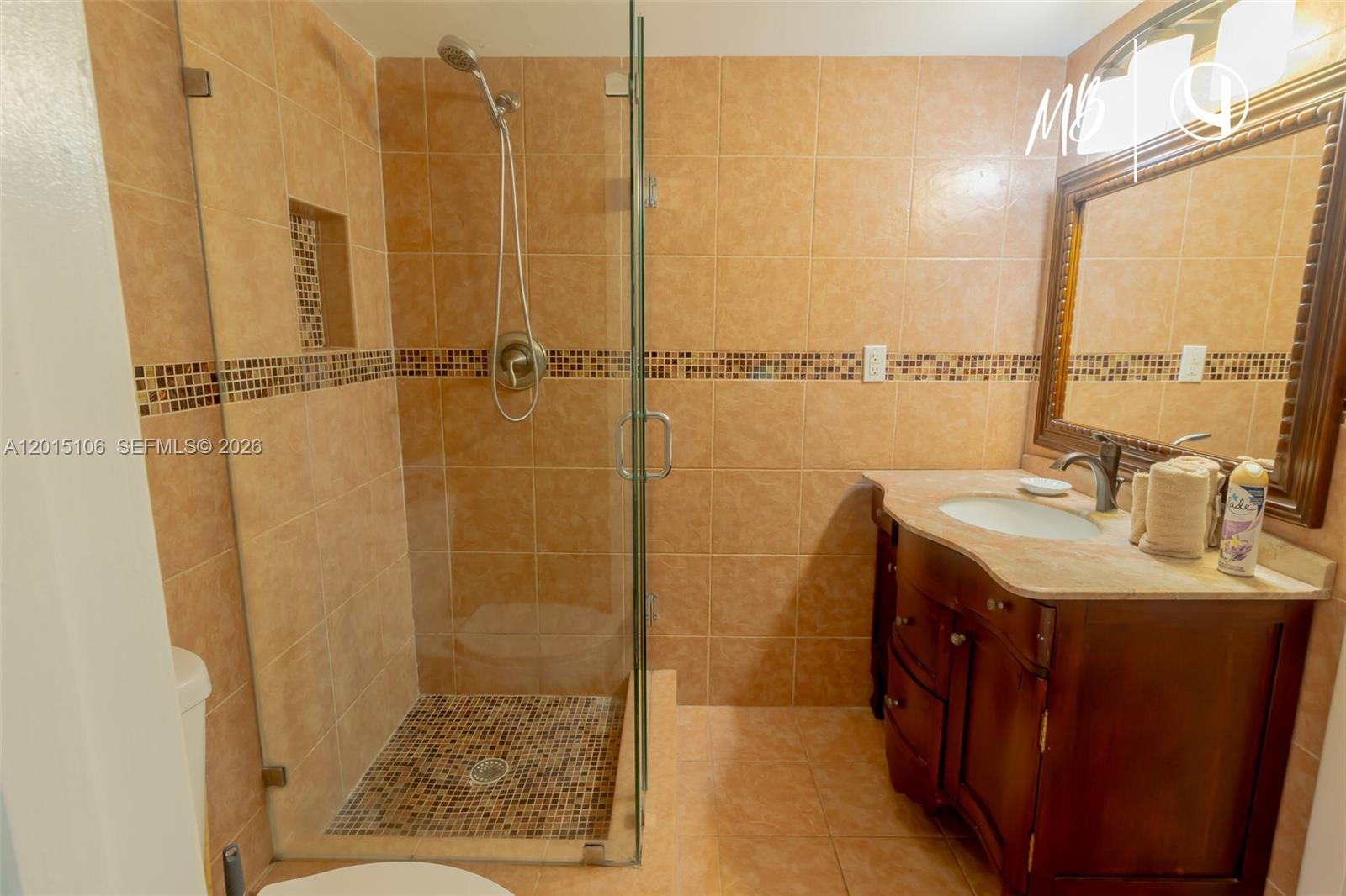 A bathroom features a glass-enclosed shower with tiled walls and a wooden vanity — SUNNY ISLES BEACH, FL