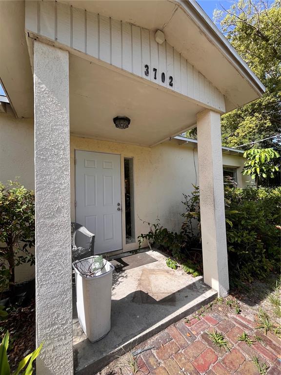 A covered entryway features a white front door, a concrete porch, and a brick walkway — 3702 OHIO AVENUE, TAMPA, FL