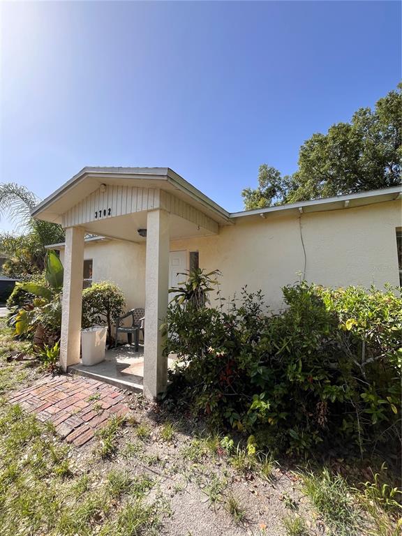 A light-colored house exterior features a covered porch entrance with a brick walkway — 3702 OHIO AVENUE, TAMPA, FL