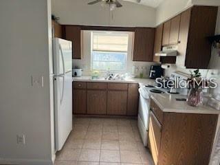 A kitchen features wood cabinets, white appliances, a tiled floor, and a window above the sink — 124 E 17TH STREET, ST CLOUD, FL