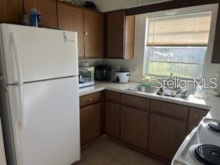 A kitchen with wood cabinets, a white refrigerator, and a window above the sink — 124 E 17TH STREET, ST CLOUD, FL