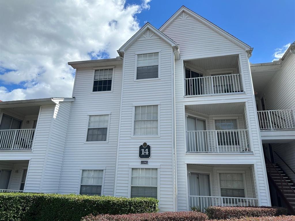 A three-story white apartment building with balconies and a building number sign — 11582 WESTWOOD BOULEVARD UNIT 1428, ORLANDO, FL