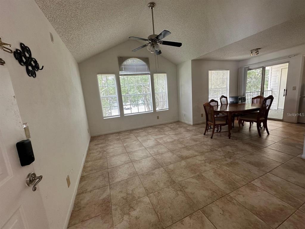 A dining area features tile flooring, a vaulted ceiling with a fan, and large windows — 11582 WESTWOOD BOULEVARD UNIT 1428, ORLANDO, FL