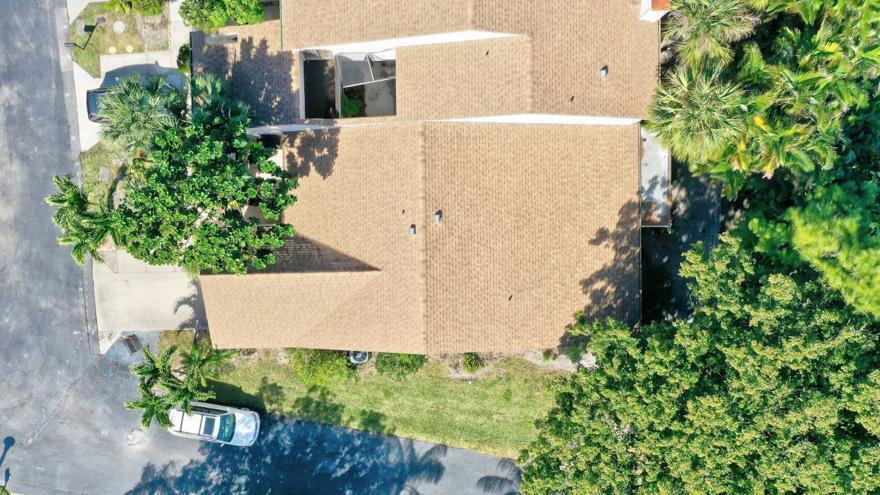 An aerial view shows a house with a brown shingled roof surrounded by green trees — 6660 Canary Palm Circle, Boca Raton FL 33433, BOCA RATON, FL