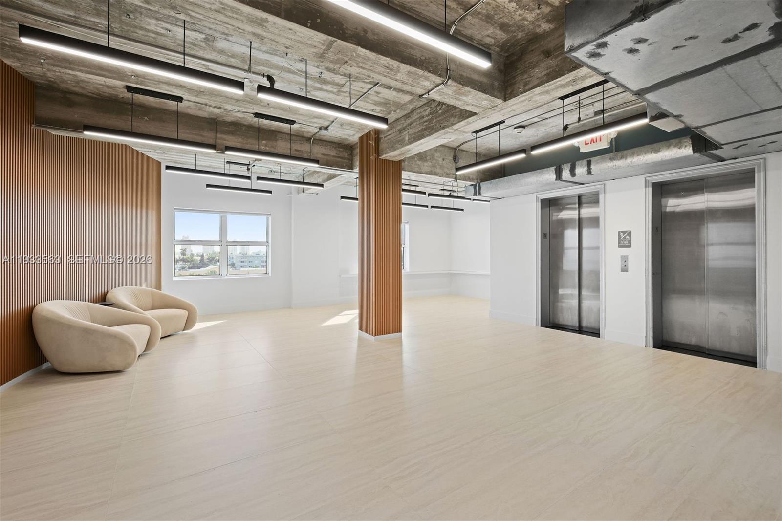 An open office lobby features concrete ceilings, wood-slat accents, tile flooring, and two elevators — 605 Lincoln Rd # 500, Miami Beach FL 33139, MIAMI BEACH, FL