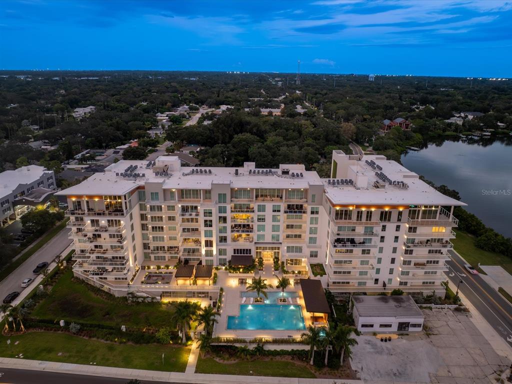 An aerial view of a multi-story apartment building with a swimming pool and surrounding landscaping — 1020 SUNSET POINT ROAD UNIT 511, CLEARWATER, FL