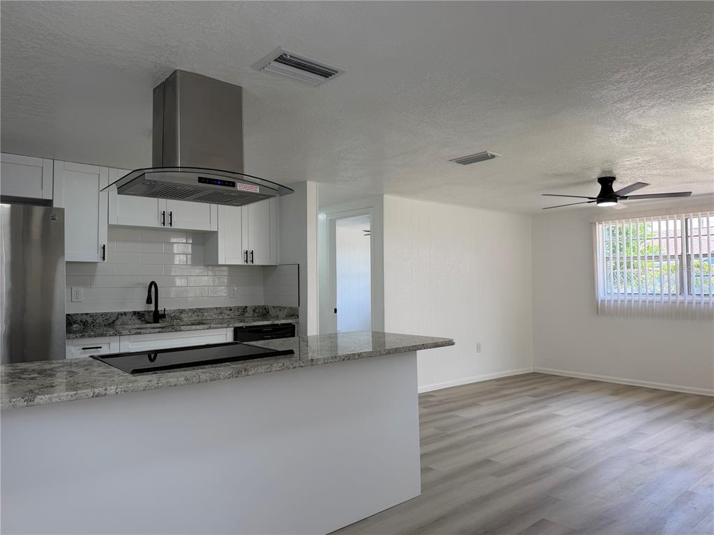 A kitchen with white cabinets, granite countertops, and a stainless steel range hood — 3821 AVENUE J NW, WINTER HAVEN, FL