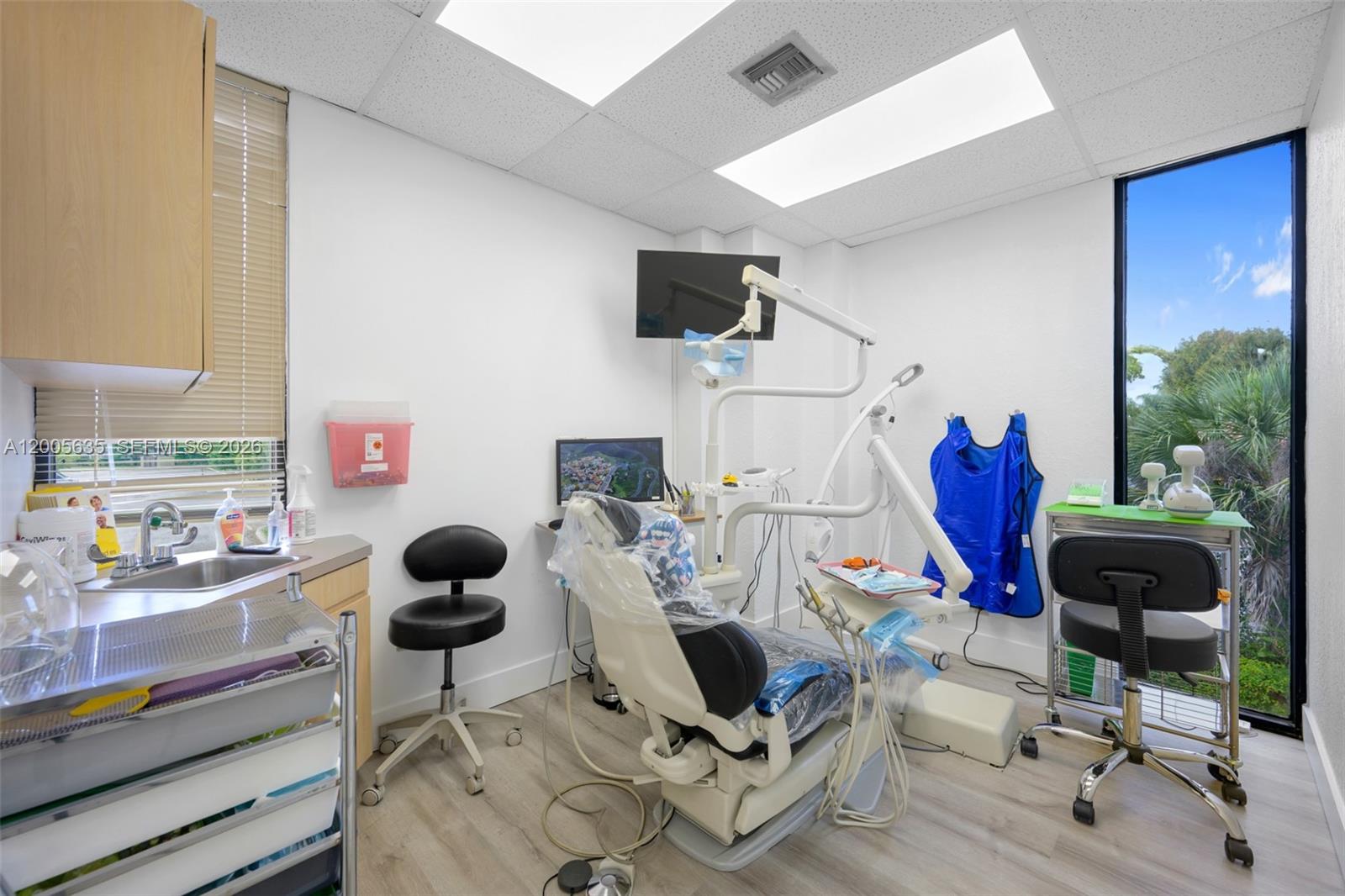 A dental exam room features a patient chair, medical equipment, a sink, and a large window — PEMBROKE PINES, FL