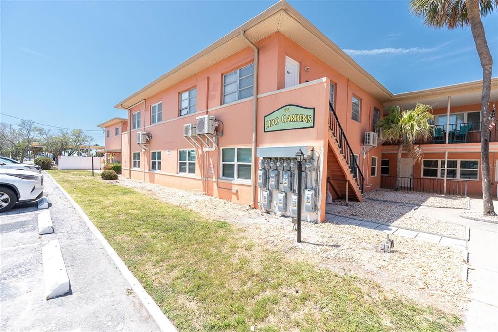 A two-story peach-colored apartment building with an exterior staircase and a parking lot — 121 46TH AVENUE UNIT 2A, ST PETE BEACH, FL