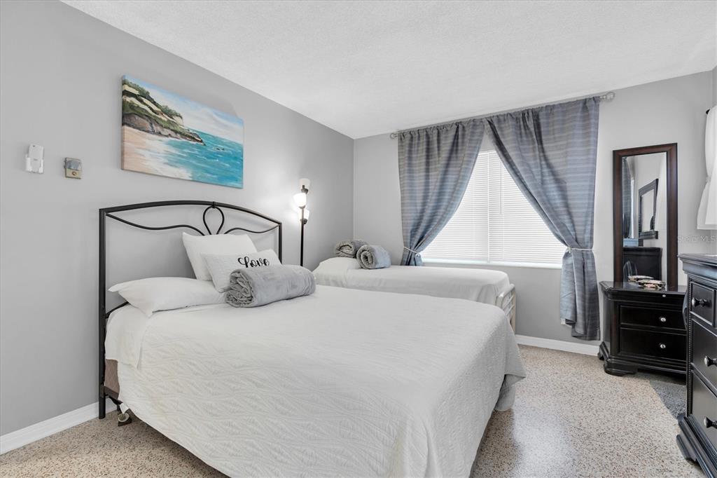 A bedroom features a queen bed, a twin bed, gray walls, and a dark dresser — 121 46TH AVENUE UNIT 2A, ST PETE BEACH, FL