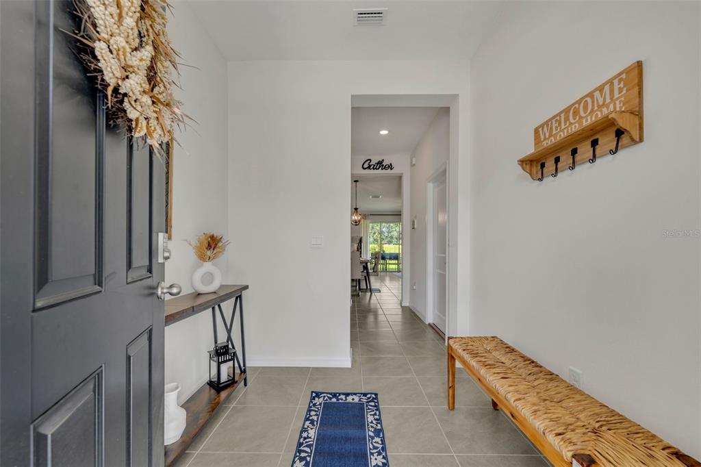 An entryway features a dark door, a wooden bench, a console table, and tile flooring — 3534 MARIGOLD PATCH COURT, PLANT CITY, FL
