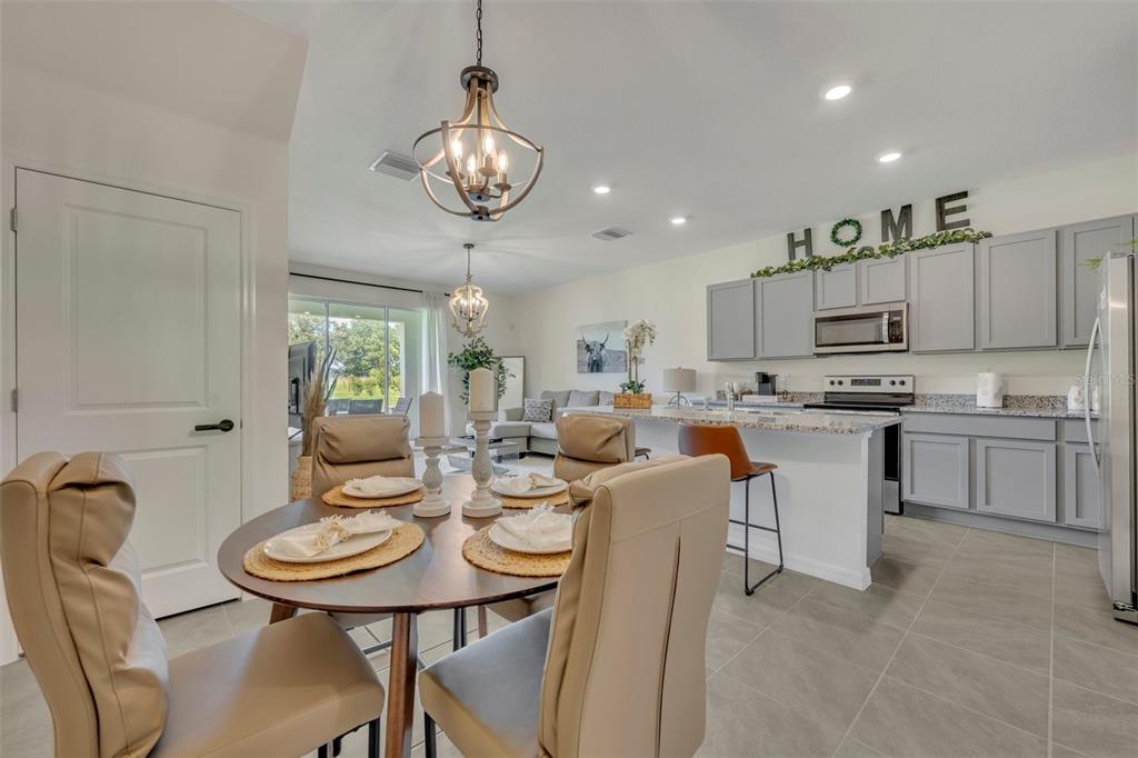 A dining area with a round table opens into a kitchen with gray cabinets — 3534 MARIGOLD PATCH COURT, PLANT CITY, FL