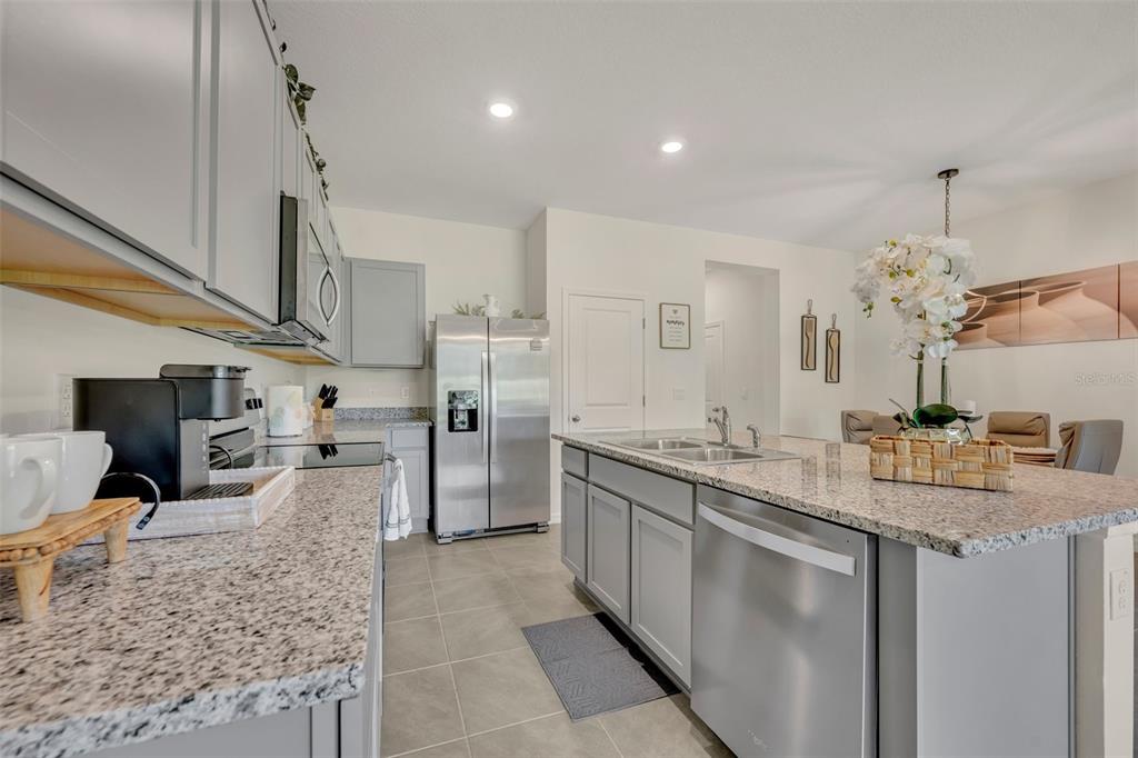 A kitchen features gray cabinets, granite countertops, stainless steel appliances, and a central island — 3534 MARIGOLD PATCH COURT, PLANT CITY, FL
