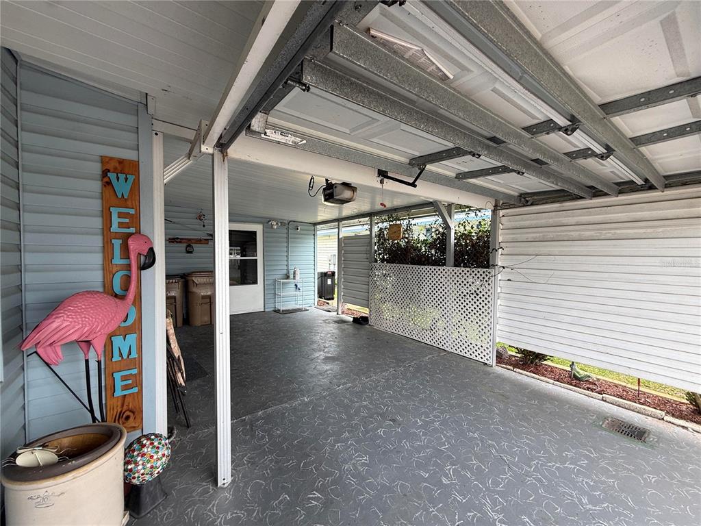 A covered carport features a concrete floor, a pink flamingo sign, and white lattice fencing — 658 MISTI DRIVE, LEESBURG, FL