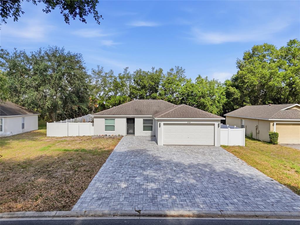 A single-story house with a paved driveway, a two-car garage, and a white vinyl fence — 313 FOGGY CREEK ROAD, DAVENPORT, FL