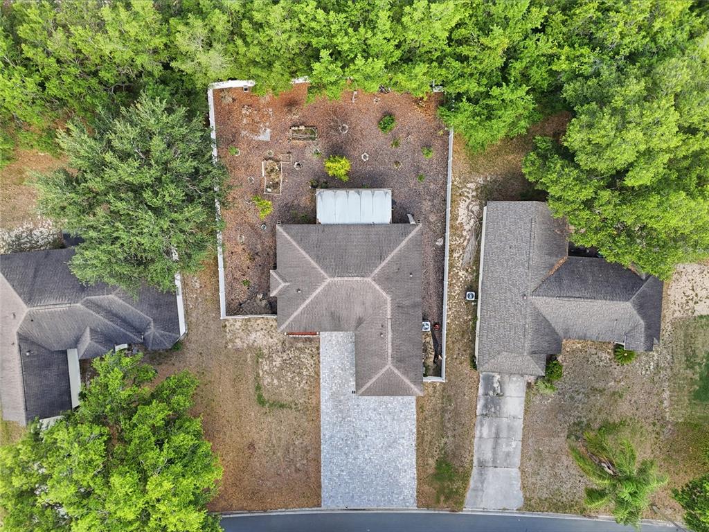An aerial view shows a house with a fenced backyard, driveway, and surrounding trees — 313 FOGGY CREEK ROAD, DAVENPORT, FL