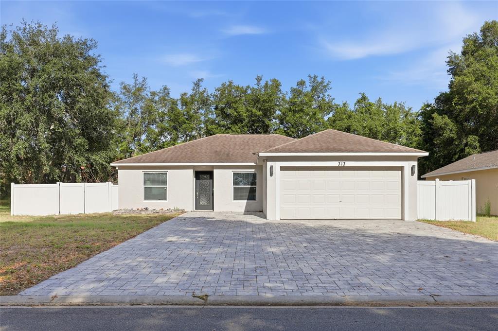 A single-story house with a paved driveway, a two-car garage, and a white vinyl fence — 313 FOGGY CREEK ROAD, DAVENPORT, FL