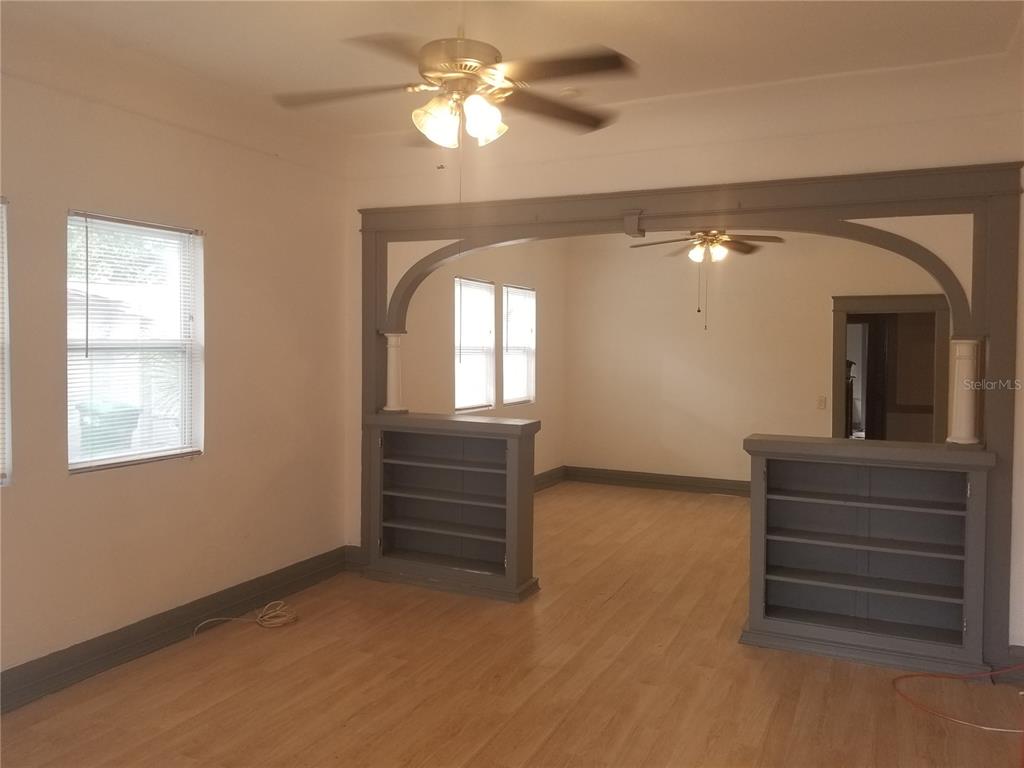 An interior view shows a living room with hardwood floors and a built-in bookshelf divider — 2107 W CHESTNUT STREET, TAMPA, FL