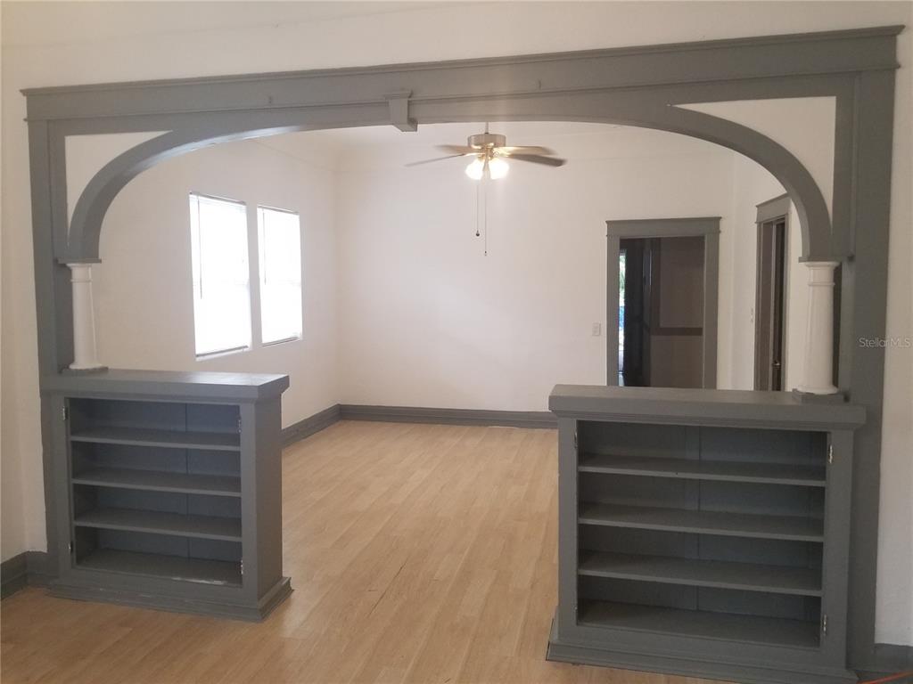A room with light wood floors features a large gray arched opening with built-in bookshelves — 2107 W CHESTNUT STREET, TAMPA, FL