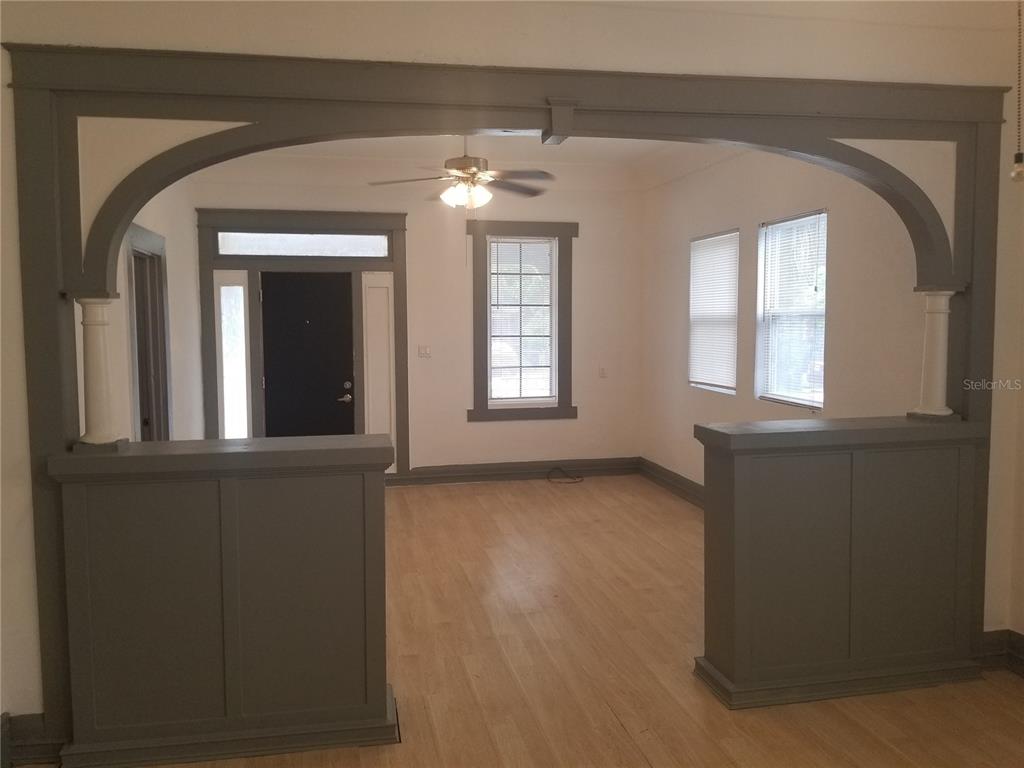 A living room features a wide arched opening with half-walls and gray painted trim — 2107 W CHESTNUT STREET, TAMPA, FL