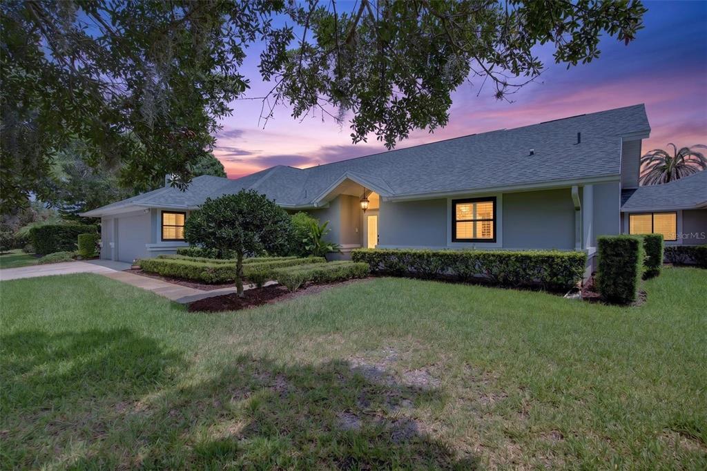 A single-story house with a gray roof, light-colored siding, and manicured hedges at dusk — 2604 ROYAL LIVERPOOL DRIVE, TARPON SPRINGS, FL