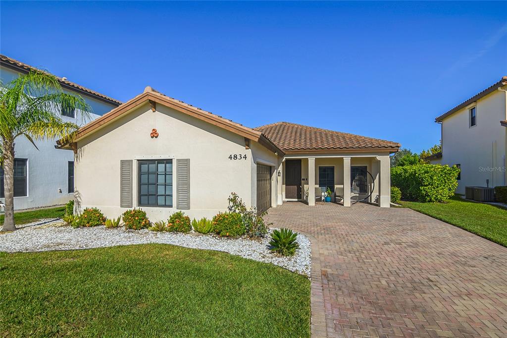 A single-story house with a stucco exterior, tile roof, and a brick paver driveway — 4834 CORRADO WAY, AVE MARIA, FL