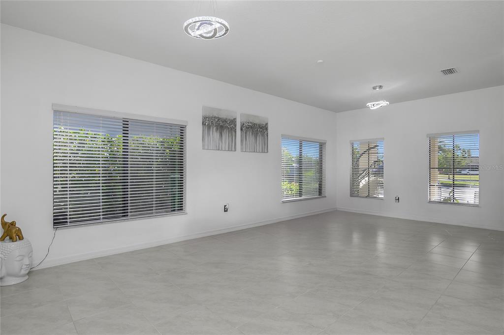 A bright, empty room features white walls, light tile flooring, and several windows with blinds — 4834 CORRADO WAY, AVE MARIA, FL