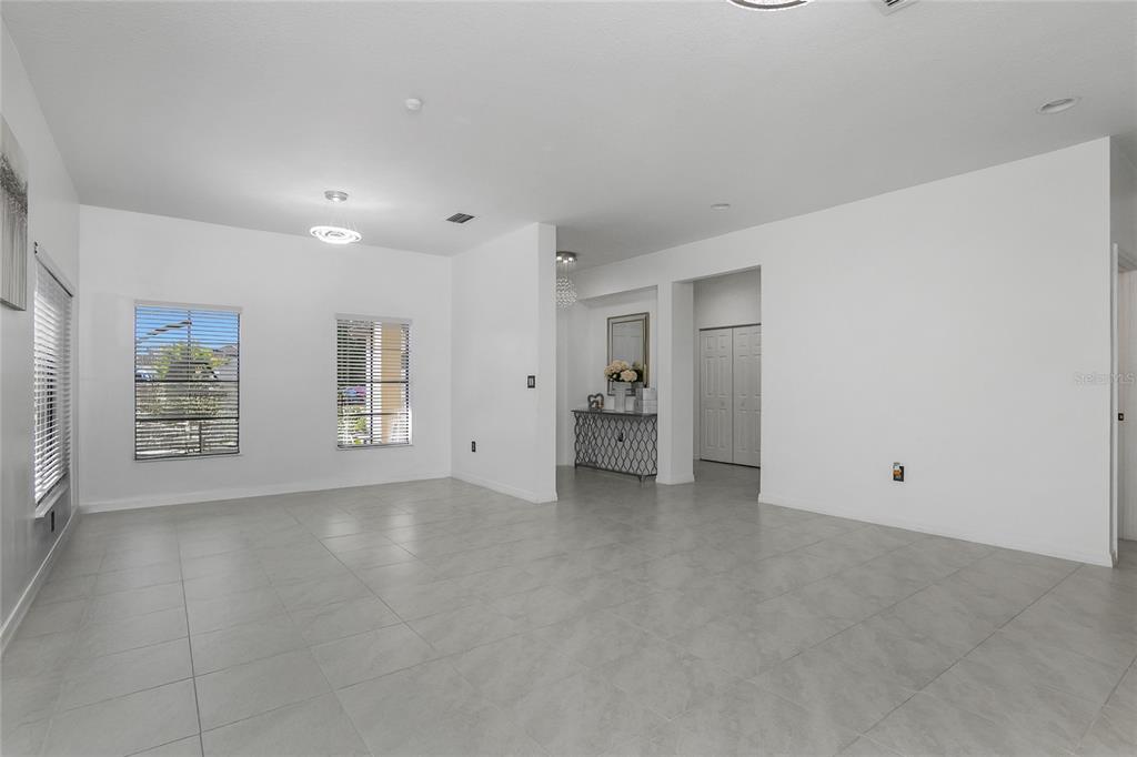 A bright, open-concept living area features white walls, large windows, and light gray tile flooring — 4834 CORRADO WAY, AVE MARIA, FL