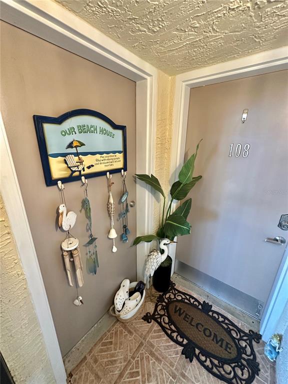 An open-concept kitchen and dining area features tiled floors, a textured ceiling, and wood cabinets — 6009 SEA RANCH DRIVE UNIT 108, HUDSON, FL