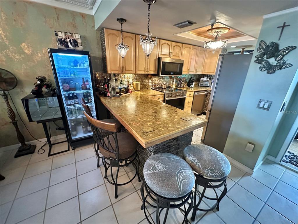 A kitchen island features a tiled countertop with a decorative bowl and metallic accents — 6009 SEA RANCH DRIVE UNIT 108, HUDSON, FL