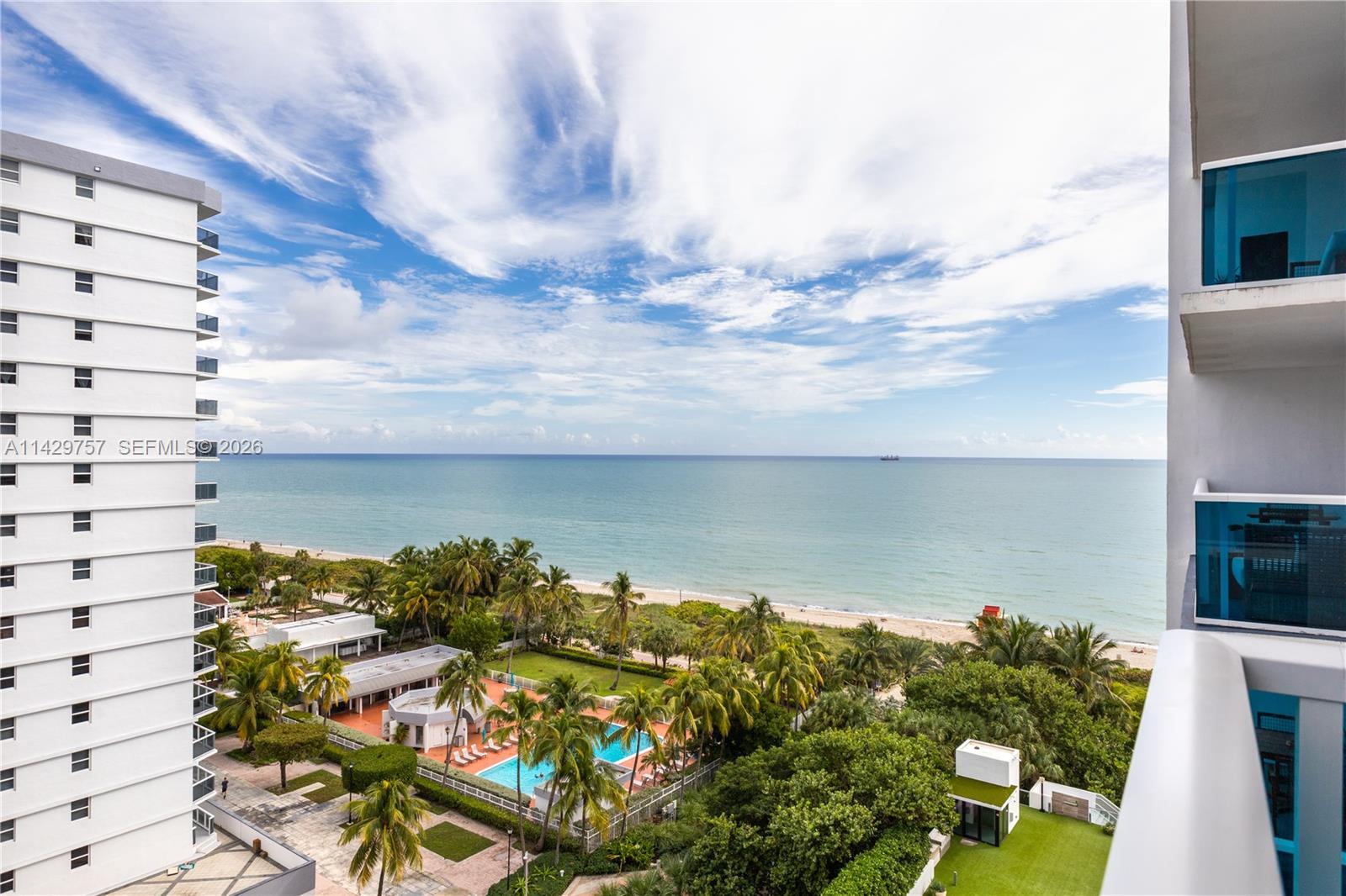 A modern open-concept kitchen and living area features white cabinetry, a wooden dining table, and balcony views — 102 24th St # 1013, Miami Beach FL 33139, MIAMI BEACH, FL