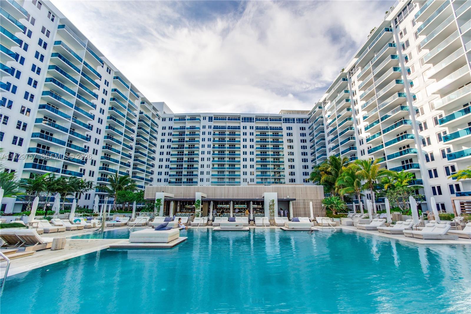 A living room features a white media console, a wall-mounted television, and a balcony overlooking the ocean — 102 24th St # 1013, Miami Beach FL 33139, MIAMI BEACH, FL
