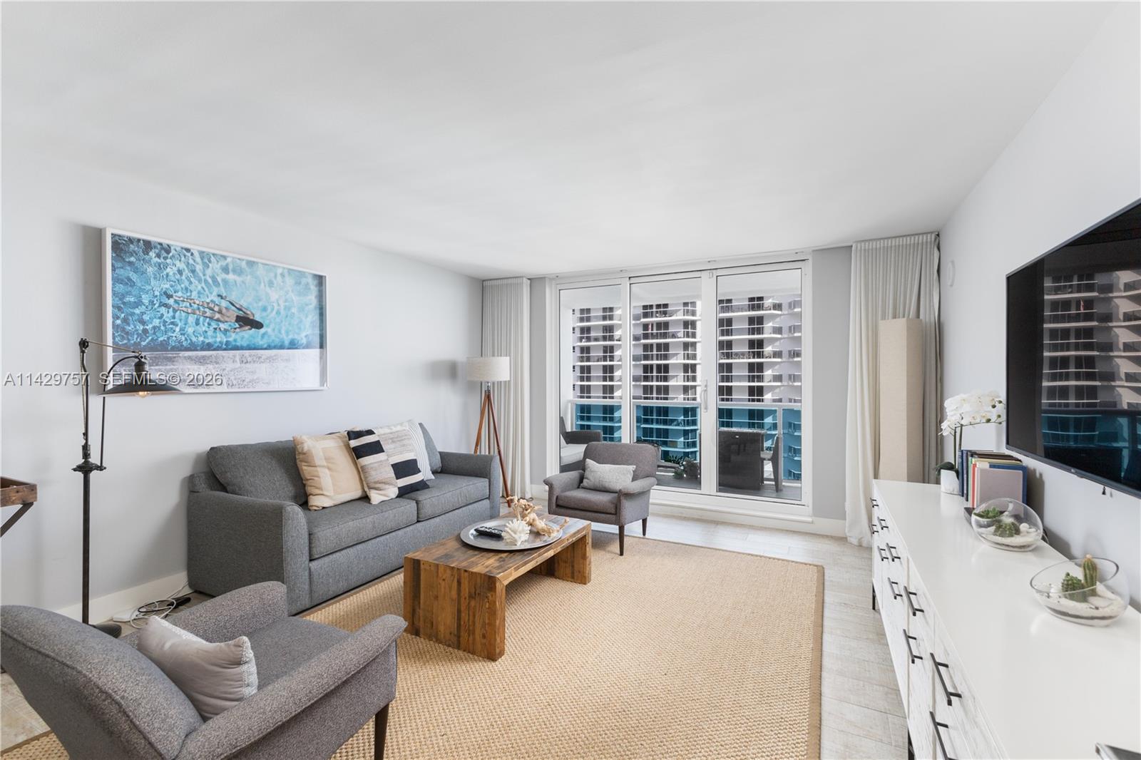 A living room and kitchen area features a gray sofa, wood coffee table, and tile flooring — 102 24th St # 1013, Miami Beach FL 33139, MIAMI BEACH, FL