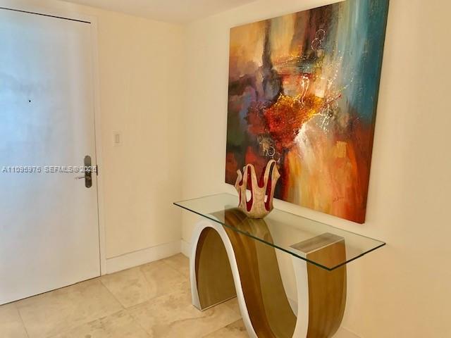 An entryway features a glass-topped console table, a large abstract painting, and tile flooring — 1830 S Ocean Dr # 4904, Hallandale Beach FL 33009, HALLANDALE BEACH, FL