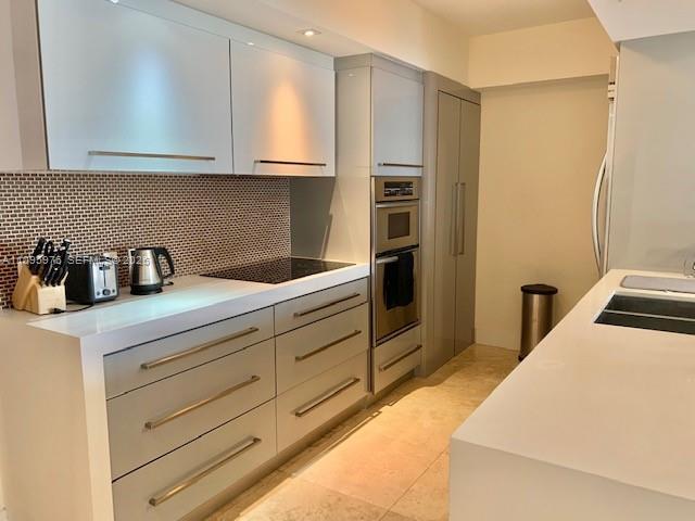 A modern kitchen features light gray cabinetry, white countertops, and a tiled backsplash — 1830 S Ocean Dr # 4904, Hallandale Beach FL 33009, HALLANDALE BEACH, FL