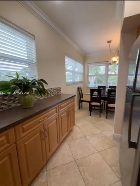 A kitchen features light wood cabinets, a dark countertop, tile flooring, and a dining area — 500 Layne Blvd # 20, Hallandale Beach FL 33009, HALLANDALE BEACH, FL
